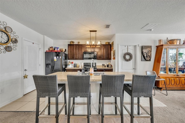 822 Sheen Cir, Haines City, FL 33844 - kitchen featuring visible vents, a kitchen island with sink, black appliances, and a breakfast bar