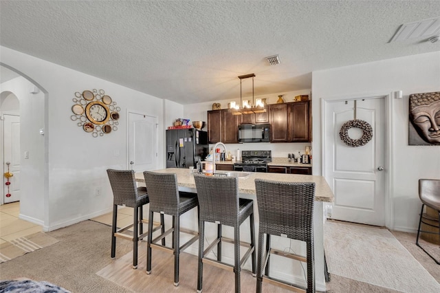 822 Sheen Cir, Haines City, FL 33844 - kitchen featuring a breakfast bar area, visible vents, arched walkways, dark brown cabinets, and black appliances