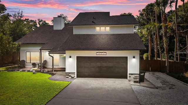 view of front of home with fence, roof with shingles, a chimney, a lawn, and driveway