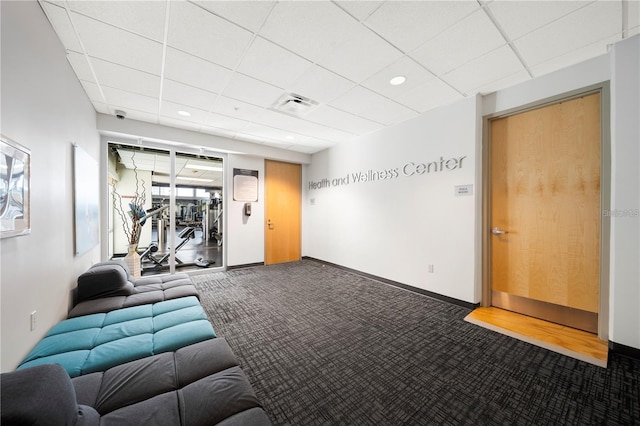 interior space featuring baseboards, a drop ceiling, and visible vents