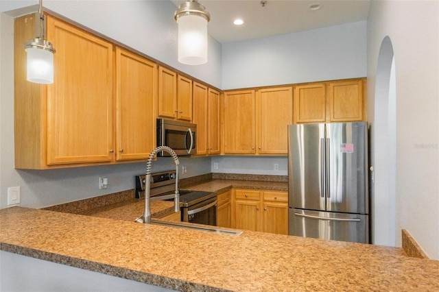 kitchen featuring appliances with stainless steel finishes, arched walkways, recessed lighting, hanging light fixtures, and a peninsula