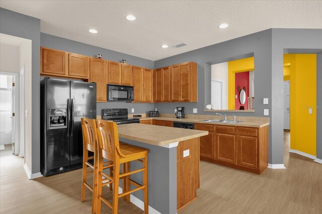 1031 Marcello Blvd, Kissimmee, FL 34746 - kitchen with a center island, light countertops, a sink, light wood finished floors, and black appliances