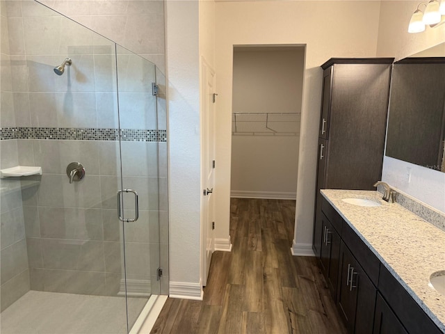 6179 Notre Dame Ter, North Port, FL 34291 - bathroom featuring wood finished floors, a stall shower, double vanity, and a walk in closet