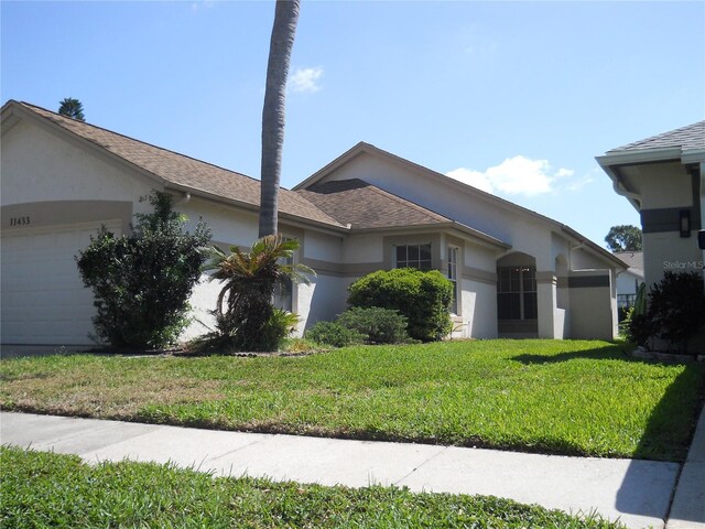 ranch-style home with a garage, stucco siding, and a front lawn