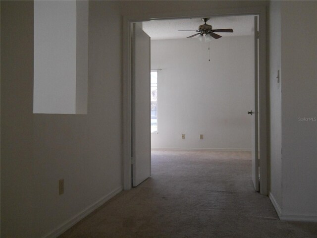 hall featuring baseboards and light carpet