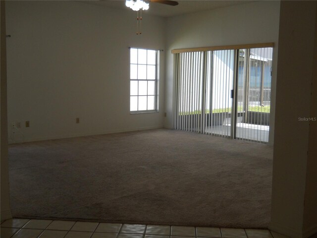 spare room featuring light tile patterned floors, baseboards, ceiling fan, and light colored carpet