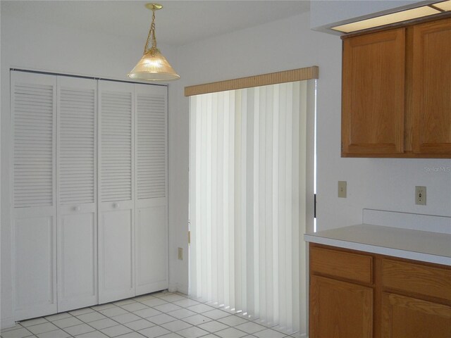 kitchen featuring light countertops, brown cabinetry, pendant lighting, and light tile patterned flooring