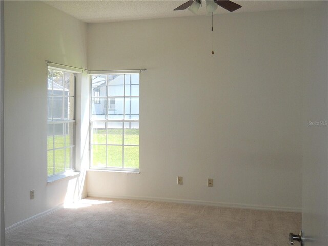 carpeted spare room with baseboards and a ceiling fan