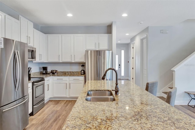 7519 Marker Ave, Kissimmee, FL 34747 - kitchen featuring a sink, light wood-type flooring, white cabinets, light stone countertops, and appliances with stainless steel finishes