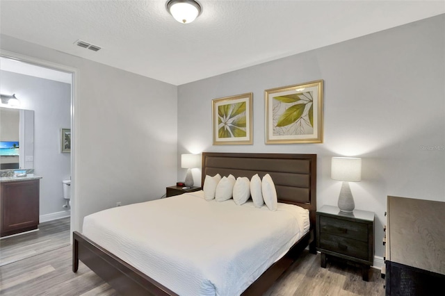 7519 Marker Ave, Kissimmee, FL 34747 - bedroom with baseboards, ensuite bathroom, visible vents, and wood finished floors