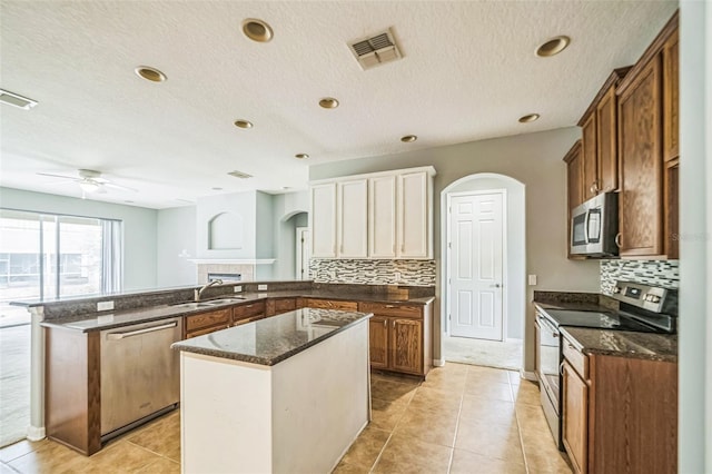 807 Ayden Oak Ln, Ocoee, FL 34761 - kitchen featuring a sink, arched walkways, dark stone counters, stainless steel appliances, and a peninsula