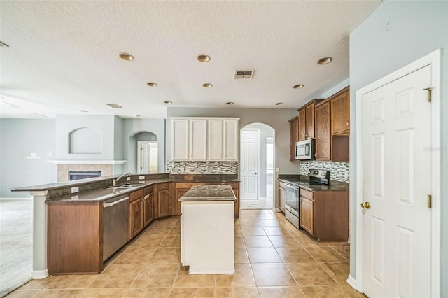 807 Ayden Oak Ln, Ocoee, FL 34761 - kitchen with visible vents, dark countertops, appliances with stainless steel finishes, a center island, and arched walkways
