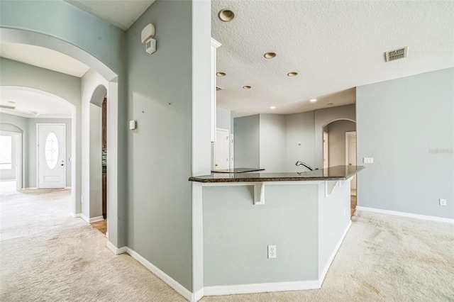 807 Ayden Oak Ln, Ocoee, FL 34761 - kitchen featuring light colored carpet, baseboards, a kitchen breakfast bar, and visible vents