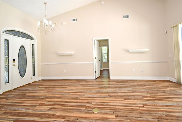 foyer entrance with visible vents, wood finished floors, a notable chandelier, and high vaulted ceiling