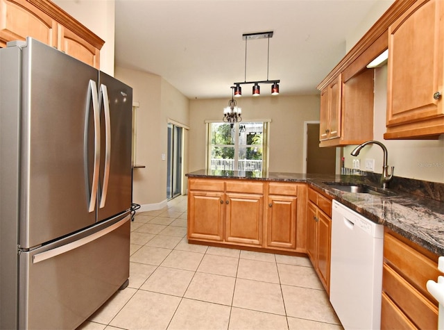 kitchen with freestanding refrigerator, a peninsula, white dishwasher, a sink, and light tile patterned floors
