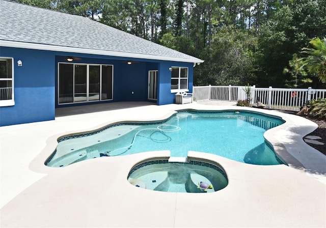 view of swimming pool with a patio, a pool with connected hot tub, and fence