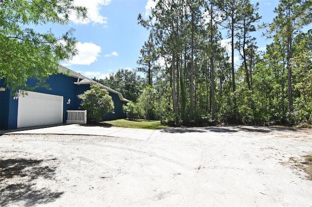 view of yard featuring a garage and concrete driveway