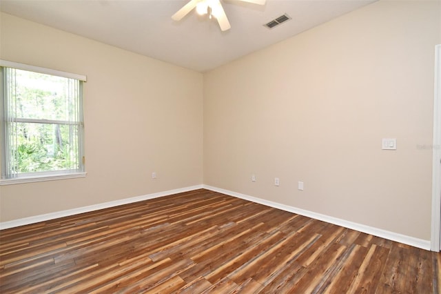 spare room with baseboards, ceiling fan, dark wood finished floors, and visible vents