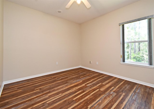 empty room with a ceiling fan, baseboards, and dark wood finished floors