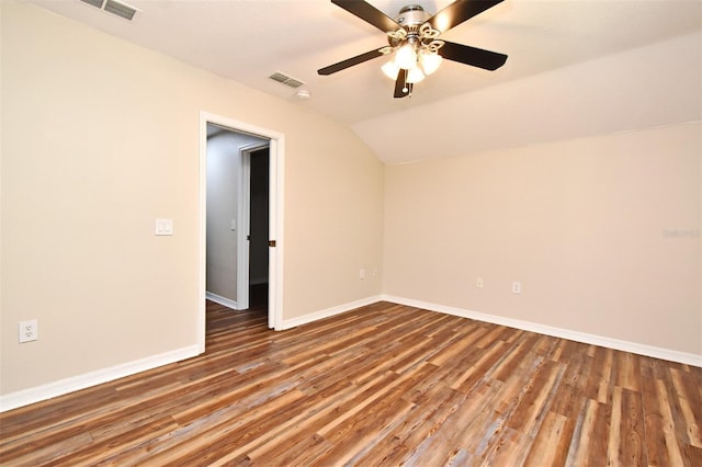 spare room featuring visible vents, baseboards, wood finished floors, and vaulted ceiling