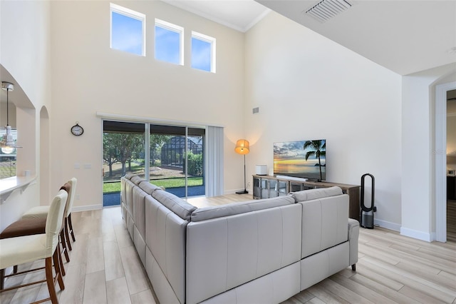 15485 Sandfield Loop, Winter Garden, FL 34787 - living room with a towering ceiling, baseboards, arched walkways, light wood-style floors, and plenty of natural light