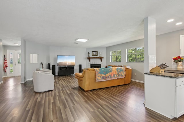 living area featuring baseboards, recessed lighting, dark wood-type flooring, and a fireplace