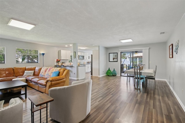 living area with visible vents, a textured ceiling, dark wood-style flooring, and baseboards
