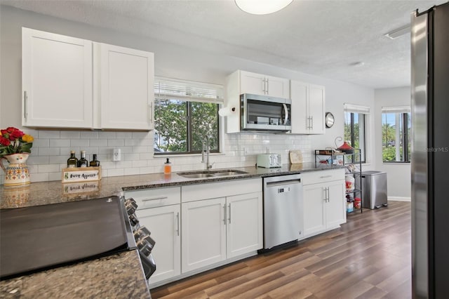 kitchen with plenty of natural light, white cabinetry, a sink, dark wood finished floors, and stainless steel appliances