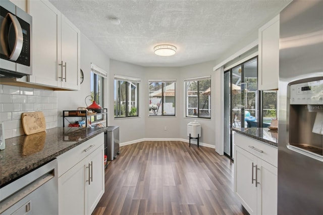 kitchen with white cabinetry, dark wood-style flooring, backsplash, and stainless steel appliances