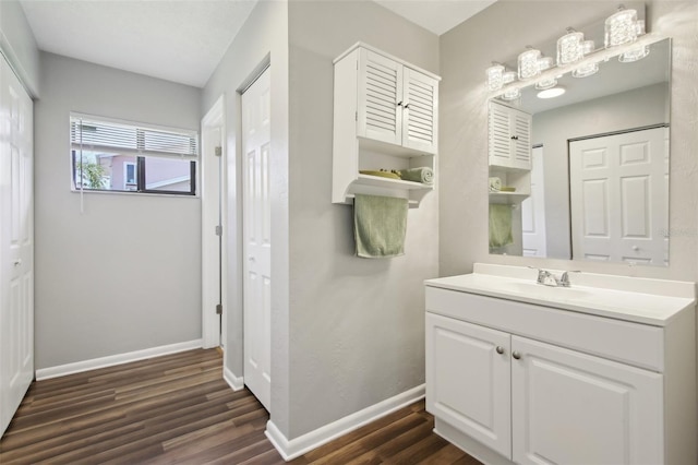 bathroom with baseboards, wood finished floors, and vanity