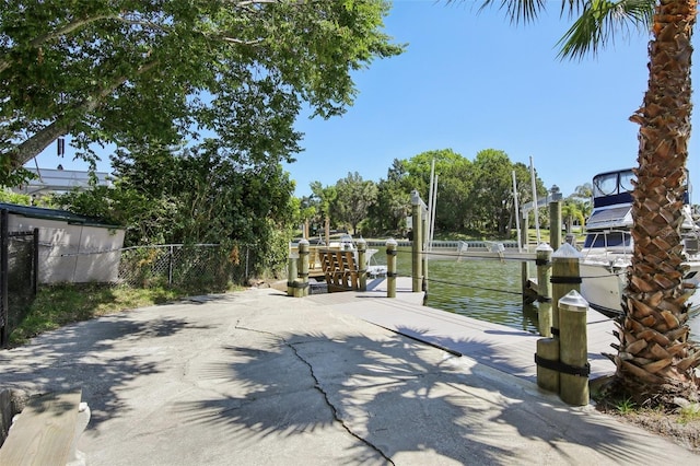 view of patio with fence, a dock, and a water view