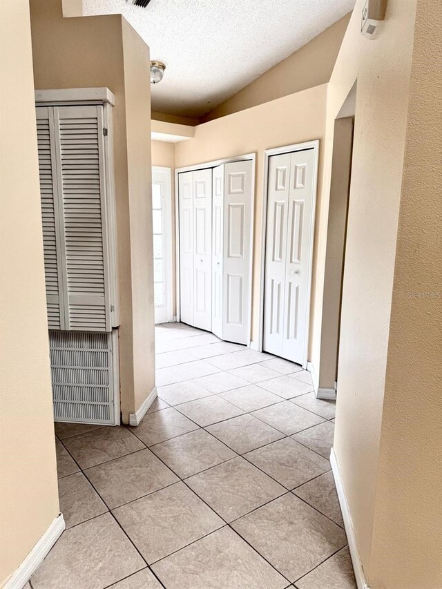 1621 Emily Ct, Kissimmee, FL 34744 - hall featuring tile patterned flooring, a textured ceiling, vaulted ceiling, and a heating unit