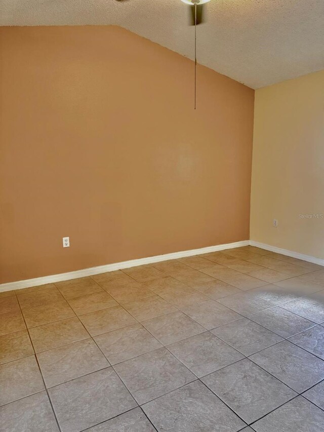 1621 Emily Ct, Kissimmee, FL 34744 - empty room featuring a textured ceiling, vaulted ceiling, and light tile patterned flooring