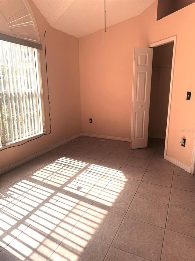 1621 Emily Ct, Kissimmee, FL 34744 - tiled empty room with vaulted ceiling and baseboards