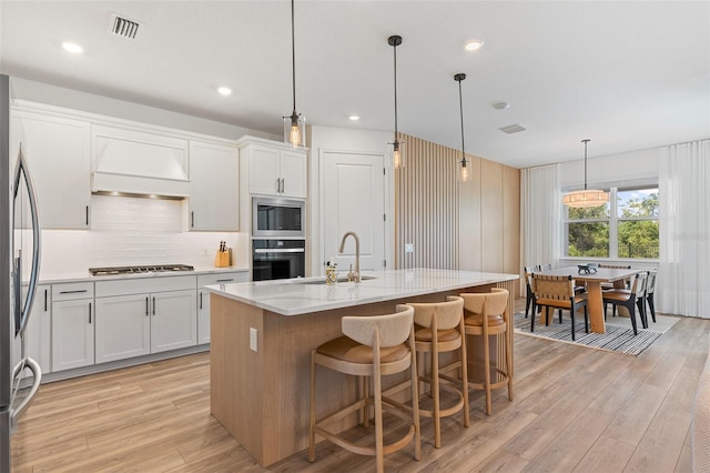 8105 Fenton St, Orlando, FL 32836 - kitchen with stainless steel appliances, premium range hood, light wood finished floors, white cabinets, and recessed lighting