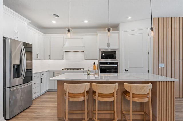 8105 Fenton St, Orlando, FL 32836 - kitchen with stainless steel appliances, light wood-style floors, light countertops, decorative backsplash, and a center island with sink