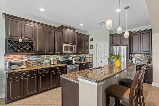 408 Egret Place Dr, Winter Garden, FL 34787 - kitchen with appliances with stainless steel finishes, a sink, light tile patterned floors, dark stone counters, and backsplash