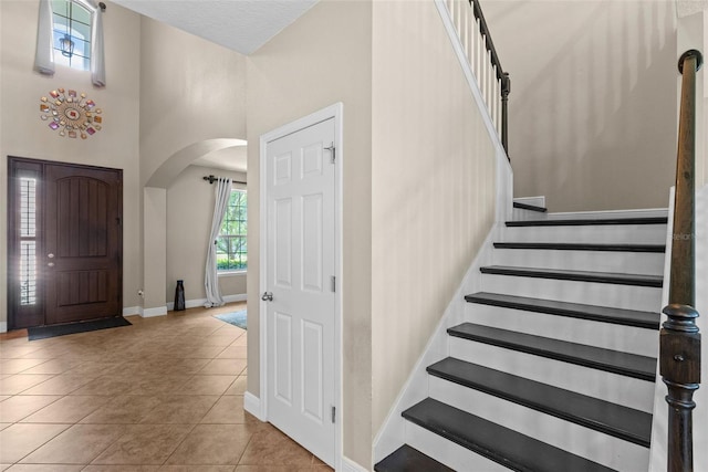 408 Egret Place Dr, Winter Garden, FL 34787 - foyer featuring arched walkways, baseboards, stairway, tile patterned floors, and a high ceiling
