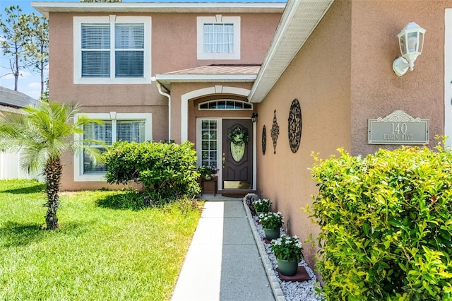 doorway to property featuring stucco siding and a yard