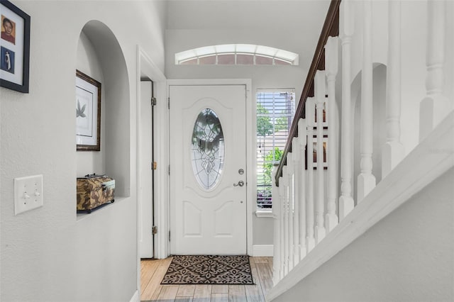 foyer featuring baseboards, stairs, and wood finished floors