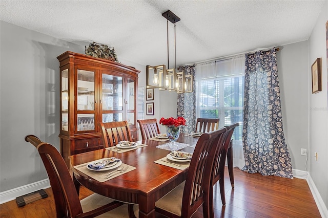 dining room with a textured ceiling, an inviting chandelier, baseboards, and hardwood / wood-style flooring