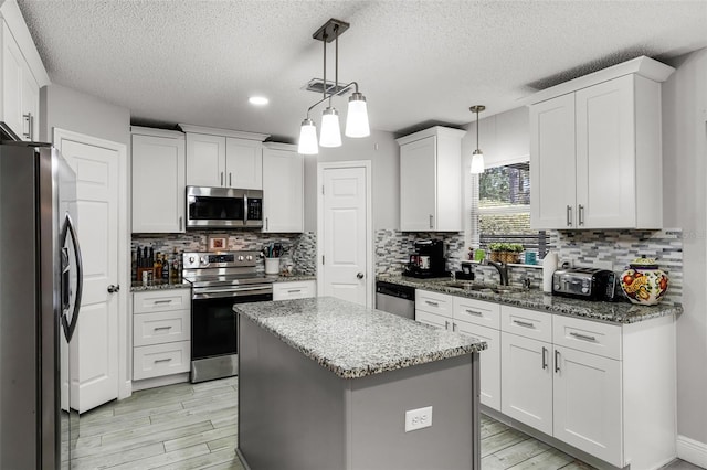 kitchen featuring stainless steel appliances, a textured ceiling, and white cabinetry