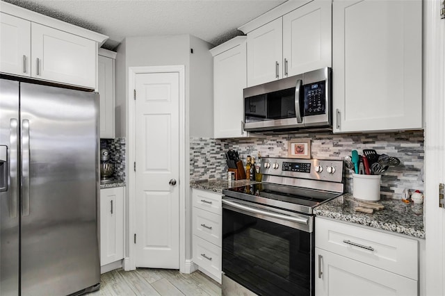 kitchen with dark stone counters, white cabinetry, and stainless steel appliances