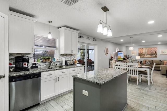 kitchen featuring visible vents, tasteful backsplash, dishwasher, a sink, and light wood-style flooring