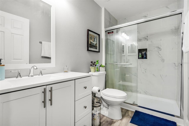 bathroom featuring vanity, wood finished floors, toilet, and a shower stall