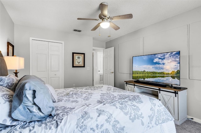 bedroom featuring carpet flooring, ceiling fan, a textured ceiling, visible vents, and a closet