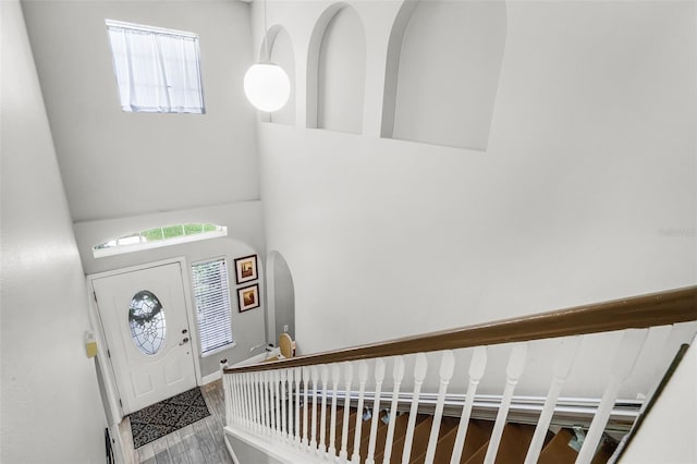 entryway with plenty of natural light, arched walkways, a towering ceiling, and wood finished floors