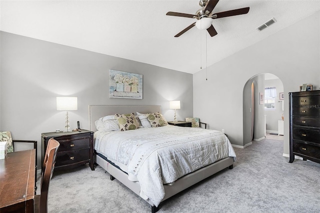 bedroom with visible vents, arched walkways, baseboards, lofted ceiling, and light carpet