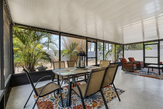 sunroom / solarium featuring a wall of windows, speckled floor, and outdoor dining space