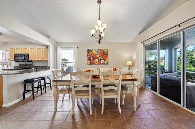 dining room with a textured ceiling, a chandelier, lofted ceiling, and tile patterned flooring
